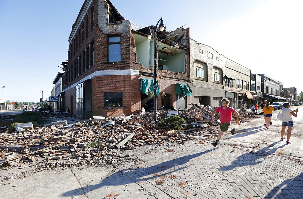A local resident runs past a tornado-damaged building on Main Street, Thursday, July 19, 2018, in Marshalltown, Iowa. Several buildings were damaged by a tornado in the main business district in town including the historic courthouse. (AP Photo/Charlie Neibergall)