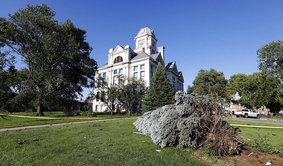An uprooted tree lies in front of the tornado damaged Marshall County Courthouse, Thursday, July 19, 2018, in Marshalltown, Iowa. Several buildings were damaged by a tornado in the main business district in town including the historic courthouse. (AP Photo/Charlie Neibergall)