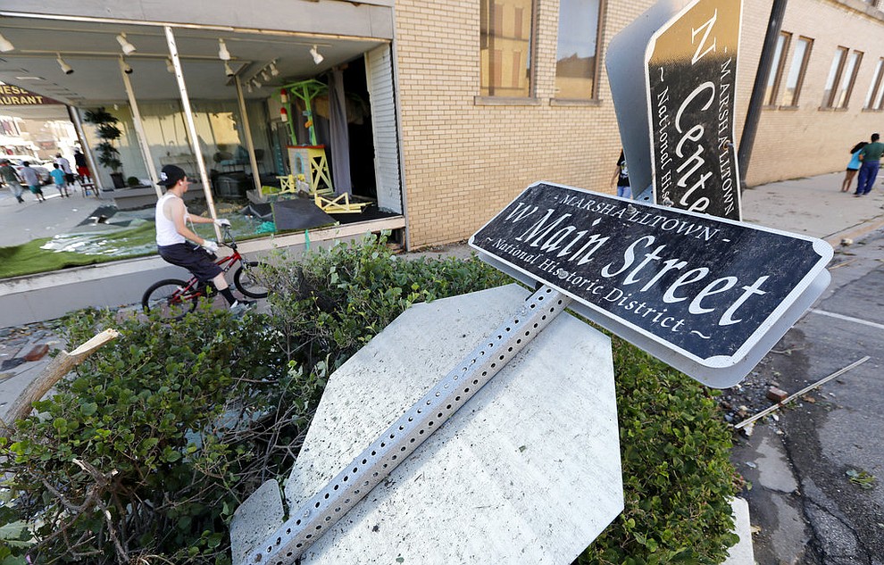 A local resident rides his bike past a toppled street sign on Main Street, Thursday, July 19, 2018, in Marshalltown, Iowa. Several buildings were damaged by a tornado in the main business district in town including the historic courthouse. (AP Photo/Charlie Neibergall)