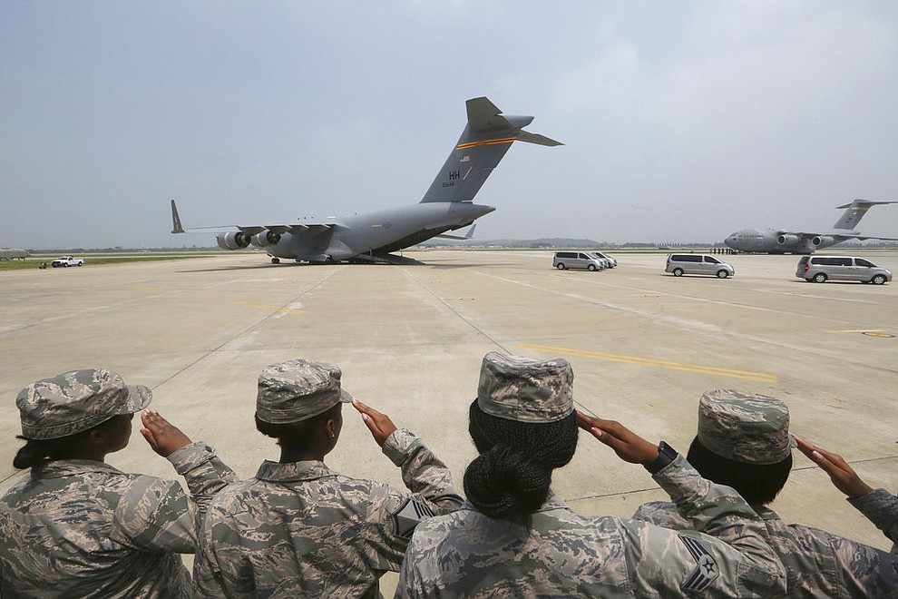 U.S. Army soldiers salute as vehicles carry remains believed to be from American servicemen killed during the 1950-53 Korean War after arrived from North Korea, at Osan Air Base in Pyeongtaek, South Korea, Friday, July 27, 2018. The U.N. Command says the 55 cases of war remains retrieved from North Korea will be honored at a ceremony next Wednesday at a base in South Korea. (AP Photo/Ahn Young-joon. Pool)