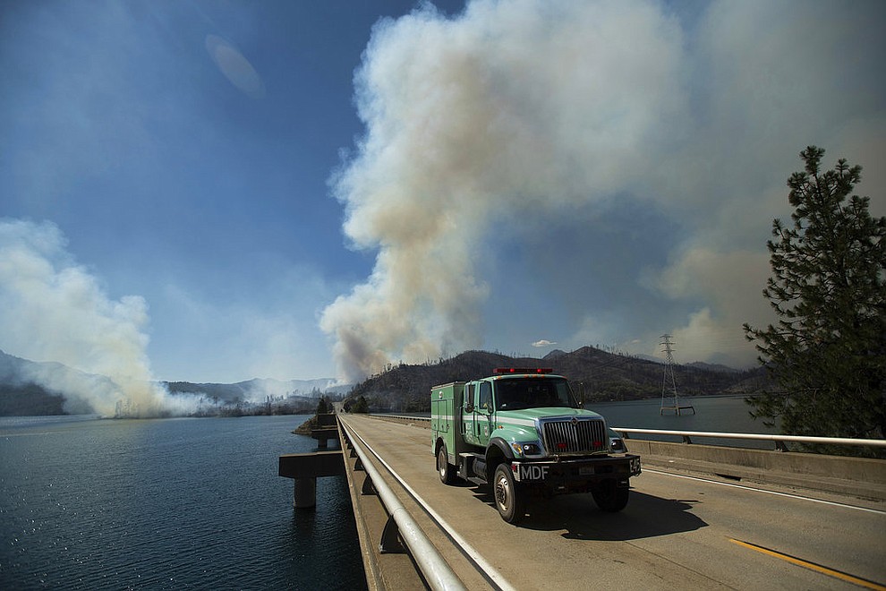 A fire truck crosses Whiskeytown Lake as the Carr Fire burns near Whiskeytown, Calif., on Thursday, July 26, 2018. (AP Photo/Noah Berger)