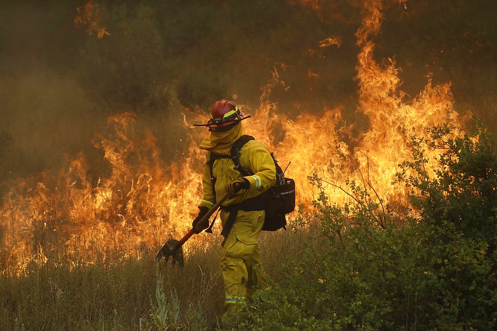 A firefighter with Cal Fire Mendocino Unit walks along a containment line as a wildfire advances Monday, July 30, 2018, in Lakeport, Calif. A pair of wildfires that prompted evacuation orders for thousands of people are barreling toward small lake towns in Northern California. (AP Photo/Marcio Jose Sanchez)