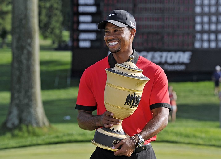 In this Aug. 4, 2013, file photo, Tiger Woods holds the trophy after winning the Bridgestone Invitational golf tournament at Firestone Country Club in Akron, Ohio. (Phil Long/AP, file)