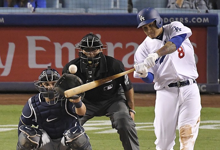 Los Angeles Dodgers' Manny Machado, right, hits a solo home run as Milwaukee Brewers catcher Manny Pina, left, watches along with home plate umpire Pat Hoberg during the ninth inning of a baseball game Monday, July 30, 2018, in Los Angeles. Milwaukee won 5-2. (Mark J. Terrill/AP)