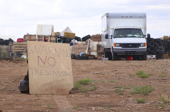 This Aug. 5, 2018 photo shows a "no trespassing" sign outside the location where people camped near Amalia, N.M. Three women believed to be the mothers of 11 children found hungry and living in a filthy makeshift compound in rural northern New Mexico have been arrested, following the weekend arrests of two men, authorities said Monday, Aug. 6. (Jesse Moya/The Taos News via AP)