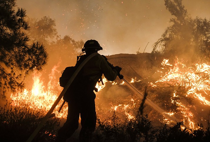 A firefighter battles the Holy Fire burning in the Cleveland National Forest along a hillside at Temescal Valley in Corona, Calif., Thursday, Aug. 9, 2018. Firefighters fought a desperate battle to stop the Holy Fire from reaching homes as the blaze surged through the Cleveland National Forest above the city of Lake Elsinore and its surrounding communities.  (AP Photo/Ringo H.W. Chiu)