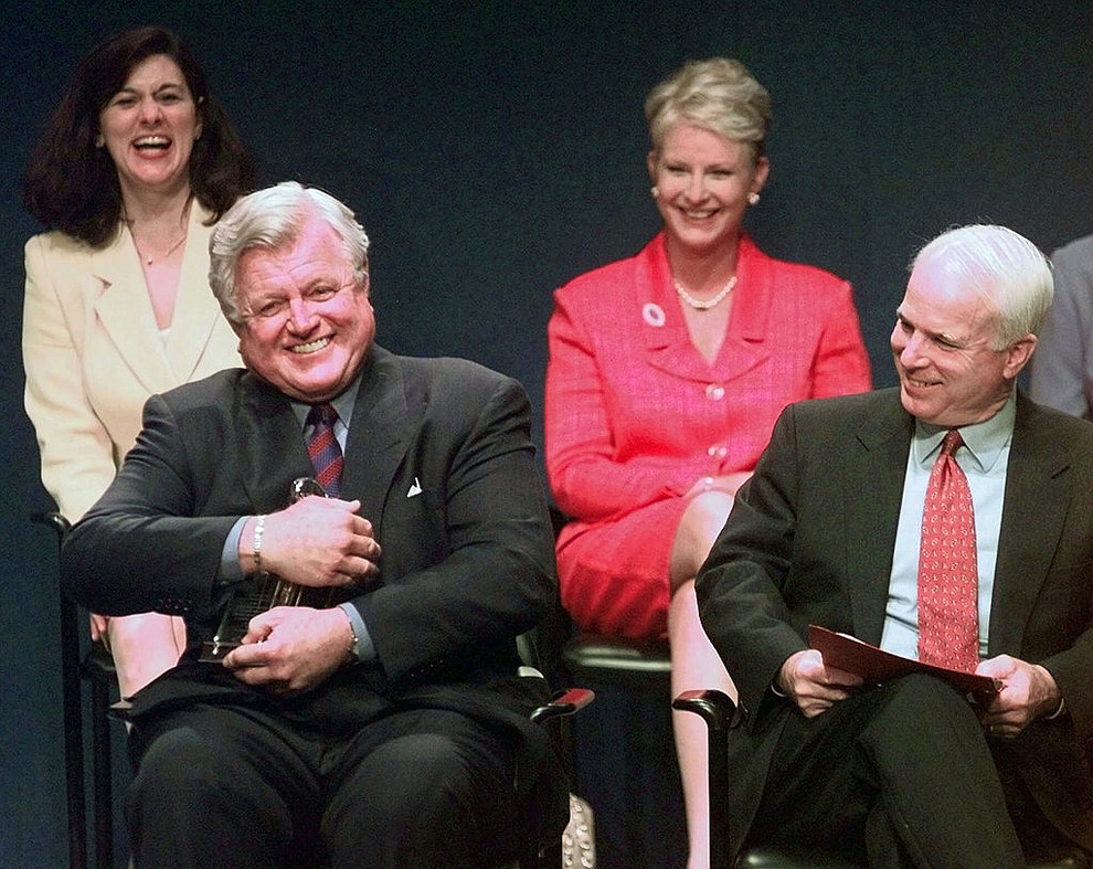 FILE - In this May 24, 1999, file photo, Sen. Edward Kennedy, D-Mass., jokingly holds the Profile in Courage award as if he intends to keep it, as co-winner, Sen. John McCain, R-Ariz., looks on at right during a ceremony at the John F. Kennedy Library in Boston. In back row are their spouses, Victoria Kennedy, left, and Cindy McCain. Arizona Sen. McCain, the war hero who became the GOP's standard-bearer in the 2008 election, has died. He was 81. His office says McCain died Saturday, Aug. 25, 2018. He had battled brain cancer. (AP Photo/Elise Amendola, File)