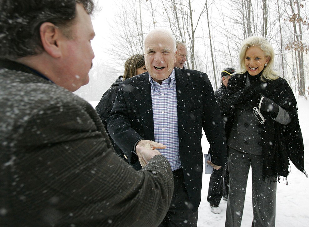 FILE - In this Jan. 1, 2008, file photo, Presidential hopeful Sen. John McCain, R-Ariz., center, and his wife, Cindy, greet Richard Brothers on their way to a house party in Tilton, N.H. Aide says senator, war hero and GOP presidential candidate McCain died Saturday, Aug. 25, 2018. He was 81. (AP Photo/Alex Brandon, File)