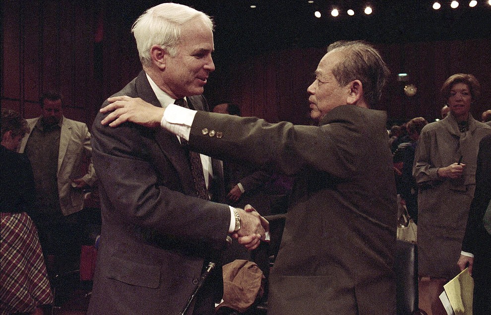 FILE - In this Nov. 7, 1991, file photo, Sen. John McCain, R-Ariz., left, is hugged by former North Vietnam Col. Bui Tin on Capitol Hill in Washington after a hearing of the Senate Select Committee on POW and MIA affairs. Tin oversaw a military prison operation dubbed the "Hanoi Hilton," where McCain was held prisoner during the Vietnam War. McCain, the war hero who became the GOP's standard-bearer in the 2008 election, died Saturday, Aug. 25, 2018. He was 81. (AP Photo/Dennis Cook, File)