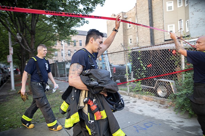 Chicago firefighters walk under tape at the scene of a fire that killed several people including multiple children Sunday, Aug. 26, 2018, in Chicago. The cause of the blaze hasn't been determined. (Erin Hooley/Chicago Tribune via AP)