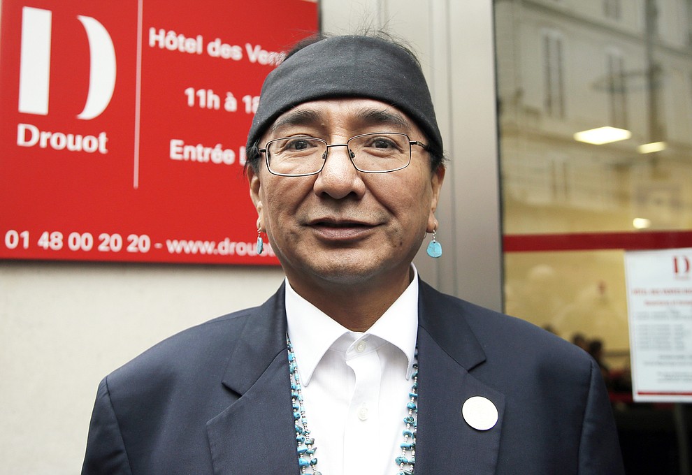 FILE - In this Dec. 15, 2014, file photo, Native American Navajo Nation Vice president, Rex Lee Jim, poses for the media outside of the Drouot's auction house prior to the contested auction of Native American Navajo tribe masks in Paris. Navajo voters have a record number of candidates to choose from in the Tuesday, Aug. 28, 2018 presidential primary election. The race has drawn 18 candidates with the top two vote-getters moving on to the November general election. (AP Photo/Francois Mori, file )