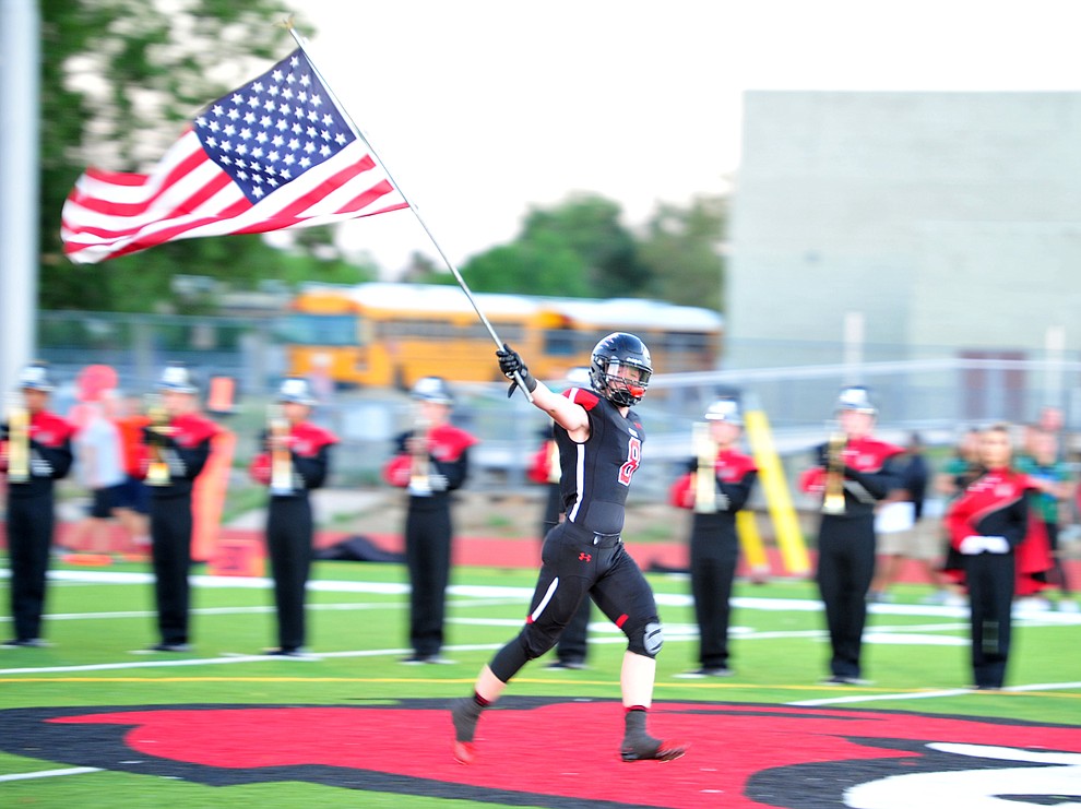 Bradshaw Mountain's Connor Scott (8) brings out the American Flag as the Bears take on the Youngker Roughriders in their home opener Friday, August 31, 2018 in Prescott Valley. (Les Stukenberg/Courier)