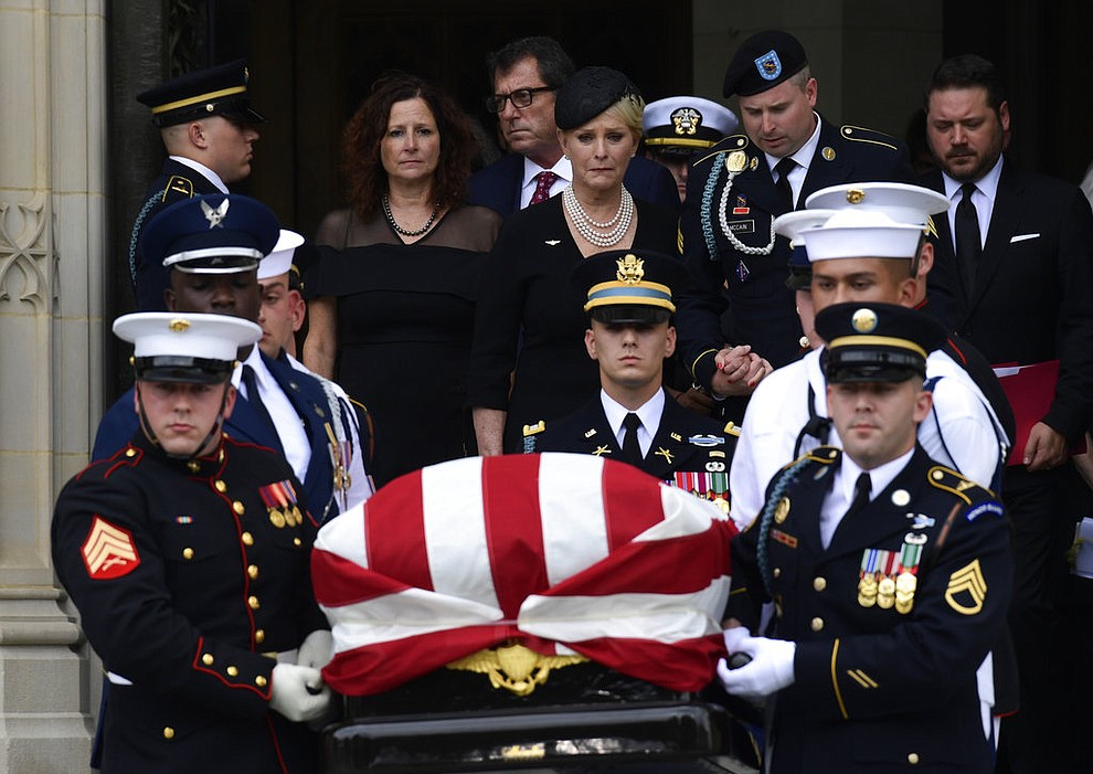 The casket of Sen. John McCain, R-Ariz., is carried out of the Washington National Cathedral in Washington, Saturday, Sept. 1, 2018, after a memorial service, as Cindy McCain is escorted by her son Jimmy McCain and other family members.  (AP Photo/Susan Walsh)