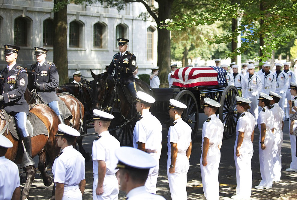 In this image provided by the family of John McCain, the horse-drawn caisson bearing the body of Sen. John McCain, R-Ariz., moves through the grounds of the United Sates Naval Academy toward the cemetery after a service in the Chapel Sunday, Sept. 2, 2018, in Annapolis, Md. (David Hume Kennerly/McCainFamily via AP)