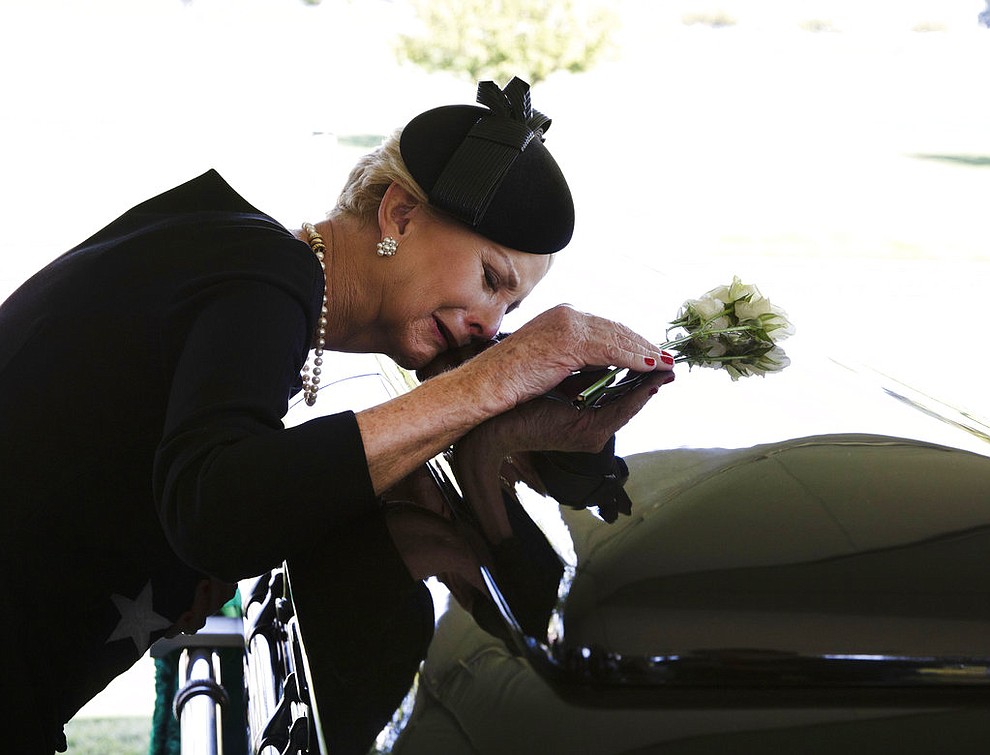 In this photo provided by the family of John McCain, Cindy McCain lays her head on the casket of Sen. John McCain, R-Ariz., during a burial service at the cemetery at the United States Naval Academy in Annapolis, Md., on Sunday, Sept. 2, 2018. (David Hume Kennerly/McCain Family via AP)