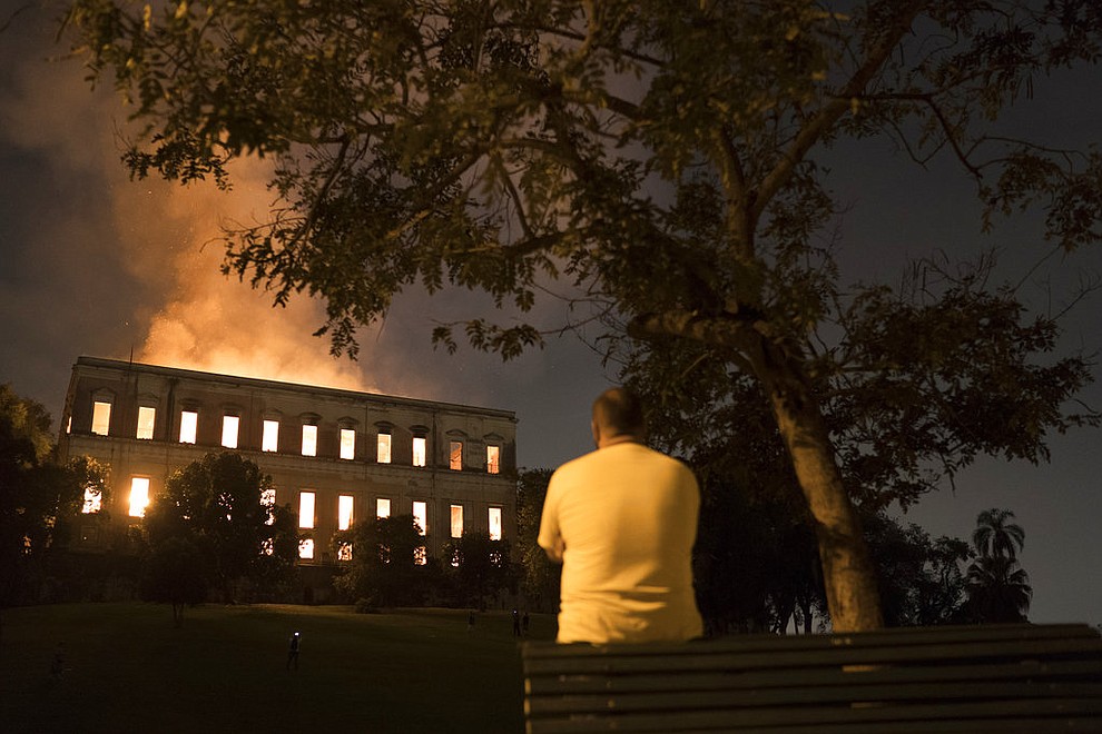 A man watches as flames engulf the 200-year-old National Museum of Brazil, in Rio de Janeiro, Sunday, Sept. 2, 2018. According to its website, the museum has thousands of items related to the history of Brazil and other countries. The museum is part of the Federal University of Rio de Janeiro. (AP Photo/Leo Correa)