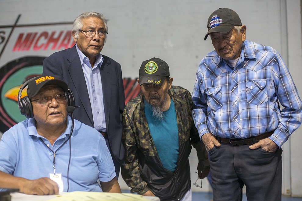 People gather to listen as Harrison Dehiya, left, of KGAK, announces the results of the Navajo Nation presidential primary, at a sports complex in Window Rock, Ariz., Tuesday, Aug. 28. 2018. (AP Photo/Cayla Nimmo)