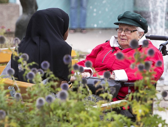 A young migrant from Africa talks to an old woman she is taking care of Aug. 30, 2018, in Flen, some 100 km west of Stockholm, Sweden. The town has welcomed so many asylum seekers in recent years that they now make up about a fourth of the population. (Michael Probst/AP Photo)