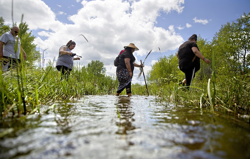 Kimberly Loring, from right, Roxanne White, Lissa Loring and George A. Hall, cross a creek looking for clues during a search for the Loring's sister and cousin, Ashley HeavyRunner Loring, who went missing in 2017 from the Blackfeet Indian Reservation in Valier, Mont., Wednesday, July 11, 2018. Kimberly has logged about 40 searches for her sister, with family from afar sometimes using Google Earth to guide her around closed roads. (AP Photo/David Goldman)