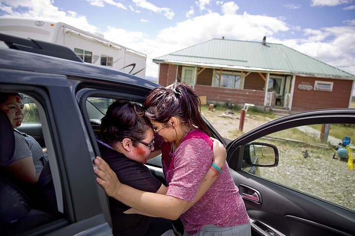 Kimberly Loring, left, touches her forehead to her little sister, Jonnilyn, 17, as she says goodbye before heading out on a search for their missing sister Ashley with their cousin, Lissa, outside their home on the Blackfeet Indian Reservation in Browning, Montana. (AP Photo/David Goldman) 