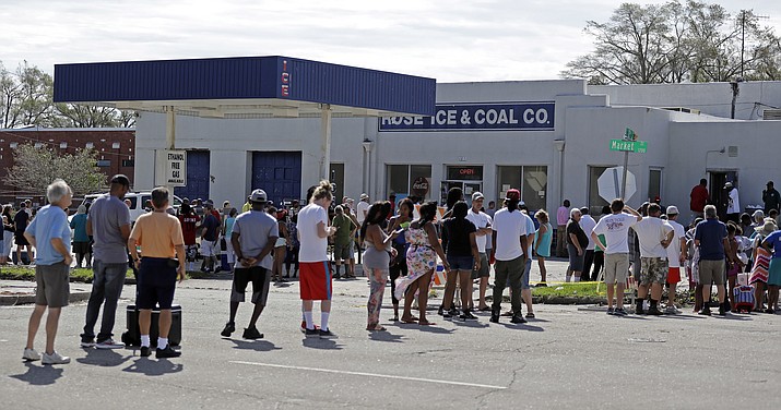 Customers line up outside Rose Ice and Coal Co. to purchase bags of ice in Wilmington, N.C. Tuesday, Sept. 18, 2018. (AP Photo/Chuck Burton)