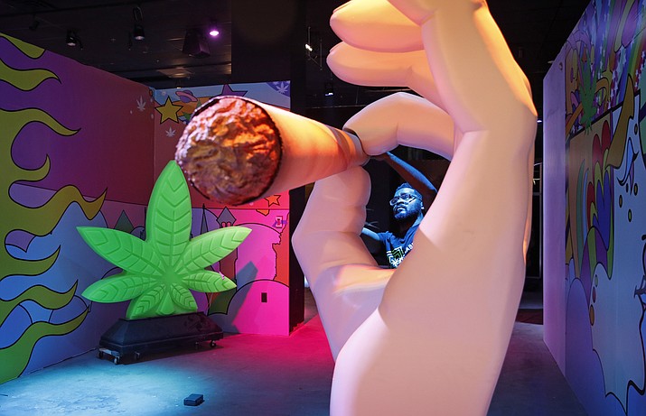 In this Tuesday, Sept. 18, 2018 photo, Gabe Williams works on a exhibit at the Cannabition cannabis museum in Las Vegas. The museum celebrating all things cannabis with displays that include a glass bong taller than a giraffe and huggable faux marijuana buds is the newest tourist attraction in Las Vegas. (AP Photo/John Locher)