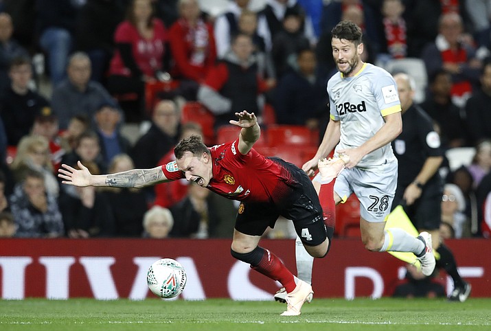 Manchester United’s Phil Jones falls with Derby County’s David Nugent, right, during the English League Cup, third round soccer match at Old Trafford in Manchester, England, Tuesday Sept. 25, 2018. (Martin Rickett/PA via AP)
