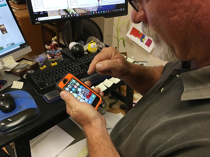Tim Wiederaenders, senior news editor for the Prescott News Network, works to bring his cellphone back to life. (Brian Bergner Jr./Courier)