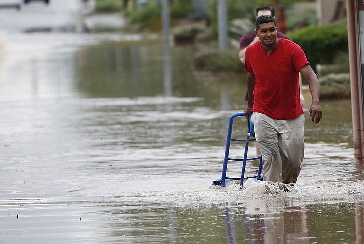 A pedestrian walks through a flooded street with a hand truck to get sand bags to deliver to local businesses during a flash flood as a result of heavy rains from tropical storm Rosa Tuesday, Oct. 2, 2018, in Phoenix. (Ross D. Franklin/AP)