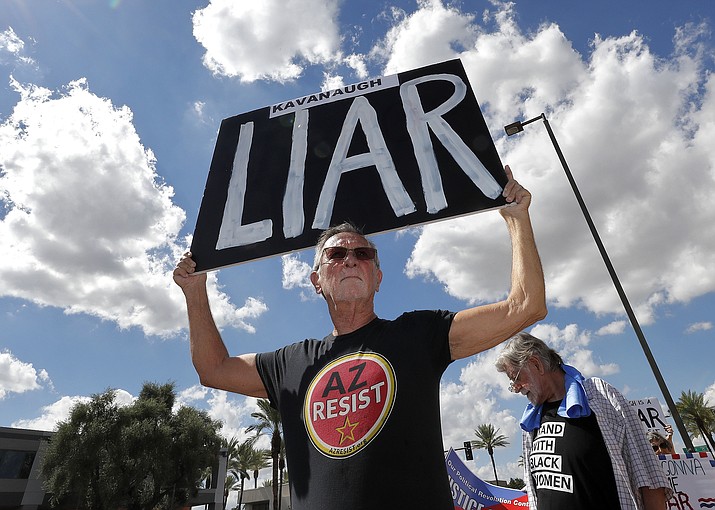 Terry Swann protests against U.S. Supreme Court nominee Brett Kavanaugh outside the office of U.S. Sen. Jeff Flake, R-Ariz., Thursday, Oct. 4, 2018, in Phoenix. (AP Photo/Matt York)