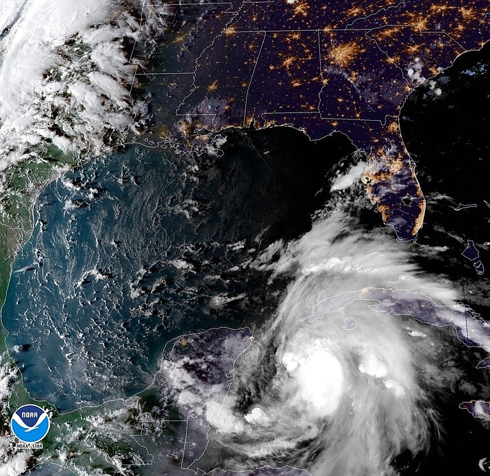 This satellite image provided by the National Oceanic and Atmospheric Administration shows a view of Tropical Storm Michael, lower right, churning as it heads toward the Florida Panhandle, Sunday, Oct. 7, 2018, at 6:52 p.m. Eastern Time. (NOAA)