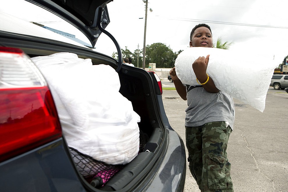 Xavier McKenzie puts a twenty pound bag of ice into his family's car in Panama City, Fla., as Hurricane Michael approaches on Tuesday, Oct.9, 2018. He and his family do not live in a storm surge area, and instead prepared for losing power for days. (Joshua Boucher/News Herald via AP)