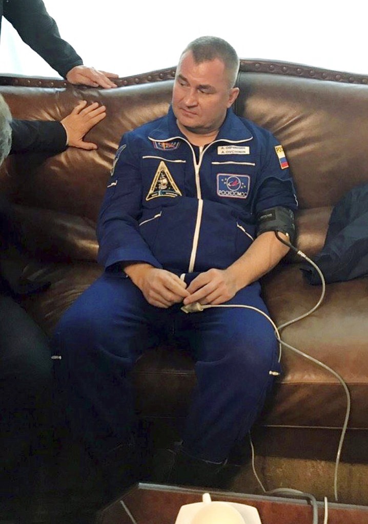 In this photo provided by Roscosmos, Russian cosmonaut Alexey Ovchinin sits in a hall after being transported by the rescue team, in Dzhezkazgan, about 450 kilometers (280 miles) northeast of Baikonur, Kazakhstan, Thursday, Oct. 11, 2018. Two astronauts from the U.S. and Russia were safe Thursday after an emergency landing in the steppes of Kazakhstan following the failure of a Russian booster rocket carrying them to the International Space Station. (Roscosmos via AP)