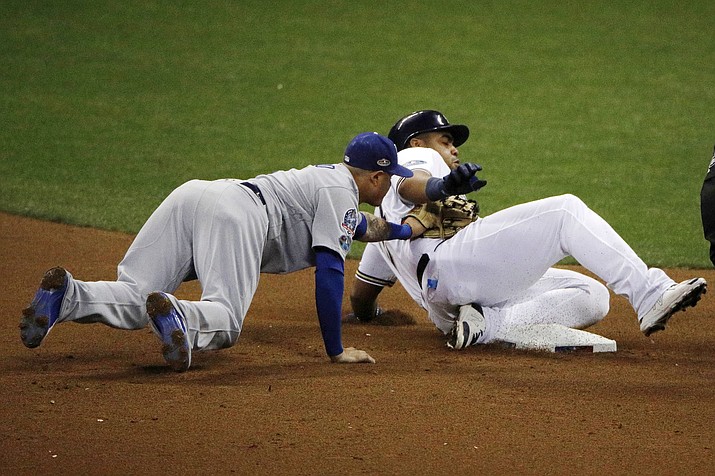 Los Angeles Dodgers shortstop Manny Machado misses a tag as Milwaukee Brewers' Jesus Aguilar slides safety into second during the seventh inning of Game 6 of the National League Championship Series baseball game Friday, Oct. 19, 2018, in Milwaukee. (Charlie Riedel/AP)