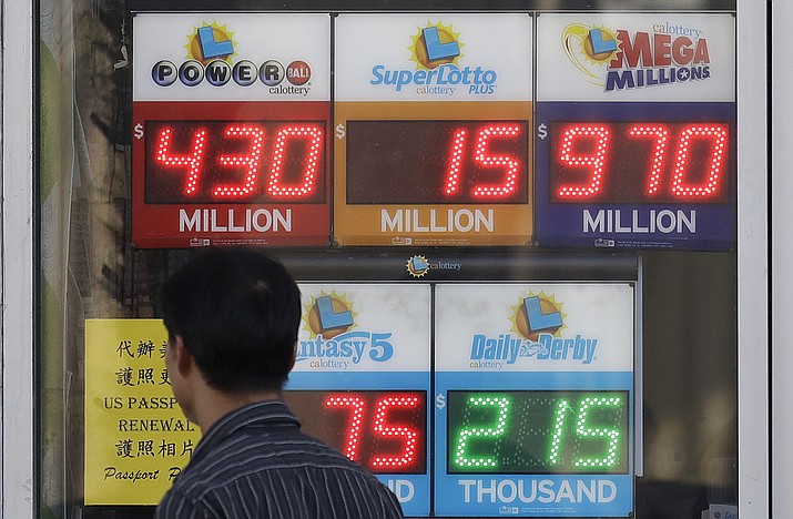 A man walks past Mega Millions and other lottery displays outside of The Lucky Spot in San Francisco, Thursday, Oct. 18, 2018. The Mega Millions jackpot has climbed to $970 million, inching ever-closer to the $1 billion mark. (Jeff Chiu/AP)