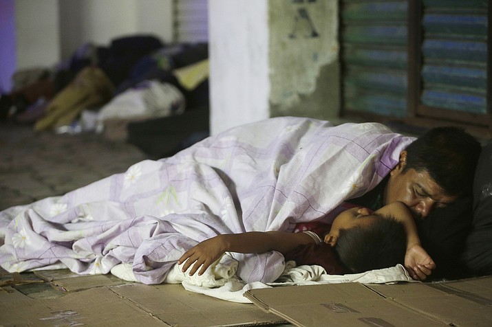 Honduran migrants hoping to reach the U.S. sleep on a sidewalk in the southern Mexico city of Tapachula, Monday, Oct. 22, 2018. Keeping together for strength and safety in numbers, some huddled under a metal roof in the city's main plaza Sunday night. Others lay exhausted in the open air, with only thin sheets of plastic to protect them from ground soggy from an intense Sunday evening shower. (Moises Castillo/AP)