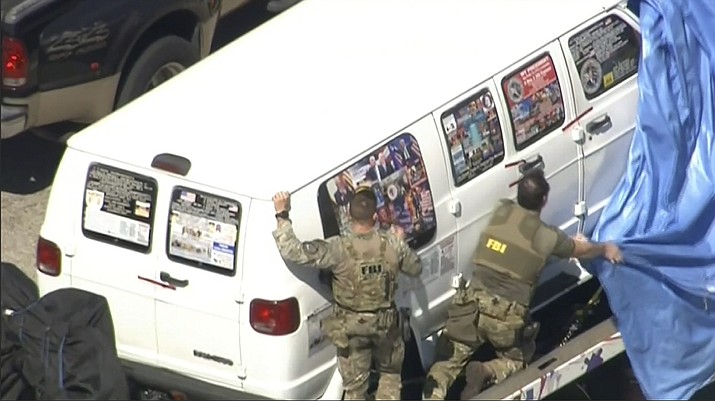 This frame grab from video provided by WPLG-TV shows FBI agents covering a van after the tarp fell off as it was transported from Plantation, Fla., on Friday, Oct. 26, 2018, that federal agents and police officers have been examining in connection with package bombs that were sent to high-profile critics of President Donald Trump. (WPLG-TV via AP)