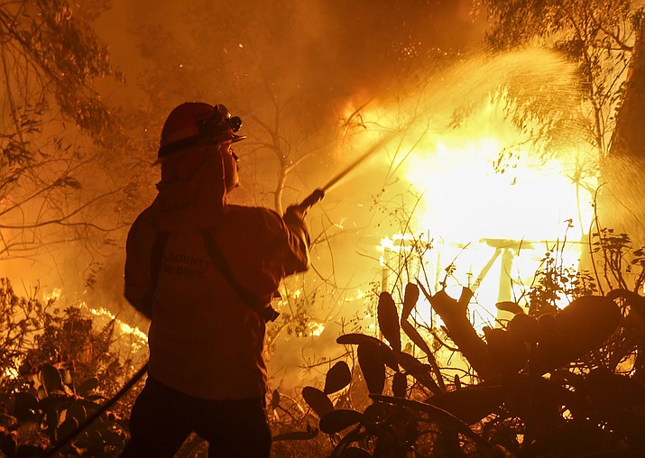 A firefighter battles the Woolsey Fire in Malibu, Calif., Friday, Nov. 9, 2018. There's no word on what sparked the Woolsey Fire and smaller Hill blaze Thursday. But winds are blamed for pushing the fire through scenic canyon communities and ridgetop homes. (AP Photo/Ringo H.W. Chiu)