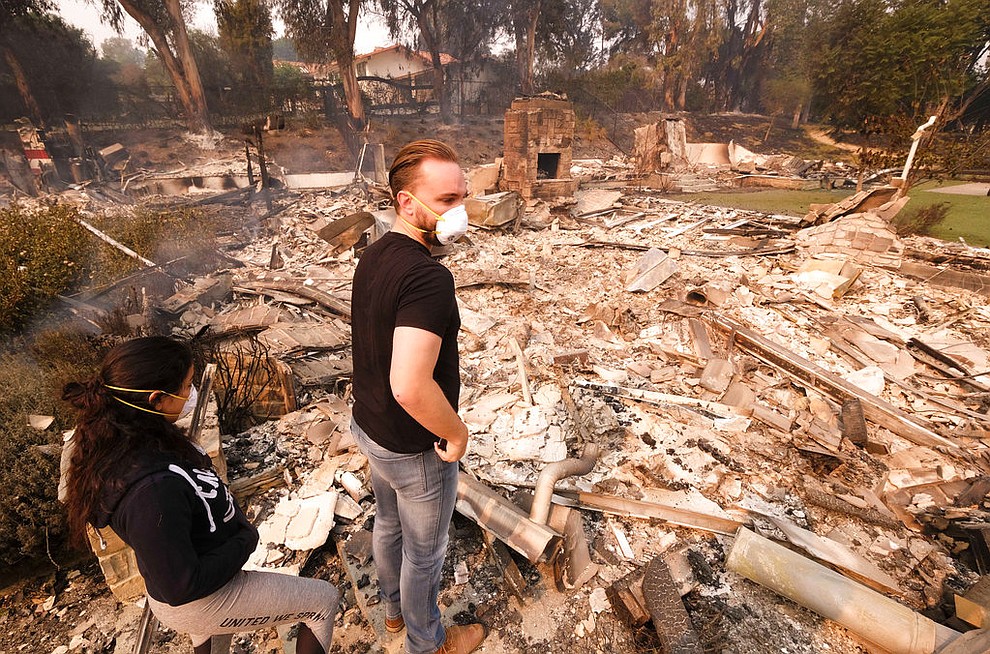 Alexander Tobolsky, right, and his girl friend Dina Arias, return to his home where burned out by the fire in Malibu, Calif., Saturday, Nov. 10, 2018.  Officials took advantage of temporarily calm conditions Saturday to assess damage from the blaze that's burned 109 square miles outside downtown Los Angeles.(AP Photo/Ringo H.W. Chiu)