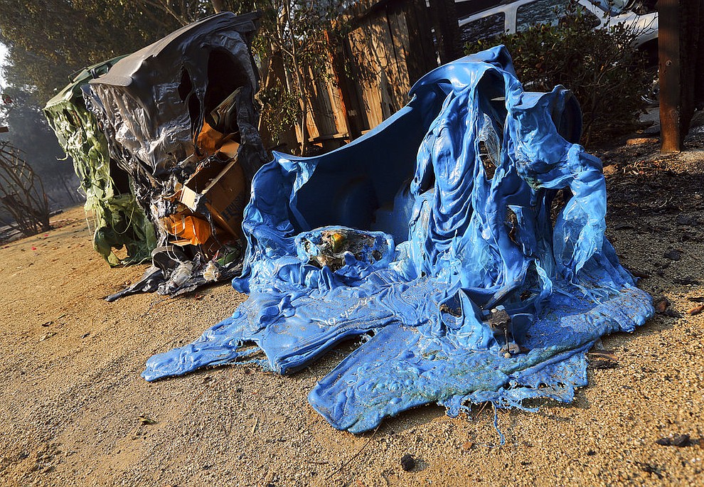 Melted recycling and trash containers stand next to one of at least 20 homes destroyed just on Windermere Drive in the Point Dume area of Malibu, Calif., Saturday, Nov. 10, 2018. Known as the Woolsey Fire, it has consumed thousands of acres and destroyed dozens of homes. (AP Photo/Reed Saxon)