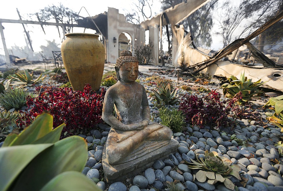A figure of Buddha stands outside one of at least 20 homes destroyed just on Windermere Drive in the Point Dume area of Malibu, Calif., Saturday, Nov. 10, 2018. Known as the Woolsey Fire, it has consumed thousands of acres and destroyed dozens of homes. (AP Photo/Reed Saxon)