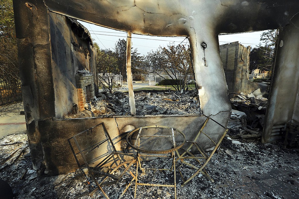 A table and chairs stand outside of one of at least 20 homes destroyed just on Windermere Drive in the Point Dume area of Malibu, Calif., Saturday, Nov. 10, 2018. Known as the Woolsey Fire, it has consumed thousands of acres and destroyed dozens of homes. (AP Photo/Reed Saxon)