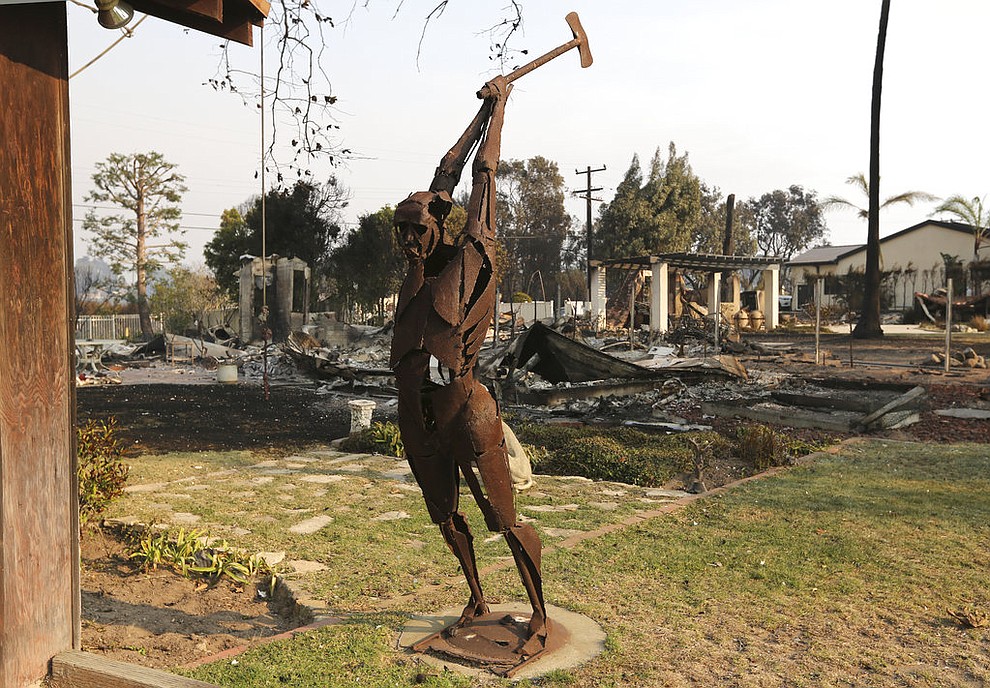 An iron figure stands in the yard of a home that survived, with others that did not in the background on Windermere Drive in the Point Dume area of Malibu, Calif., Saturday, Nov. 10, 2018. Known as the Woolsey Fire, it has consumed thousands of acres and destroyed dozens of homes. (AP Photo/Reed Saxon)