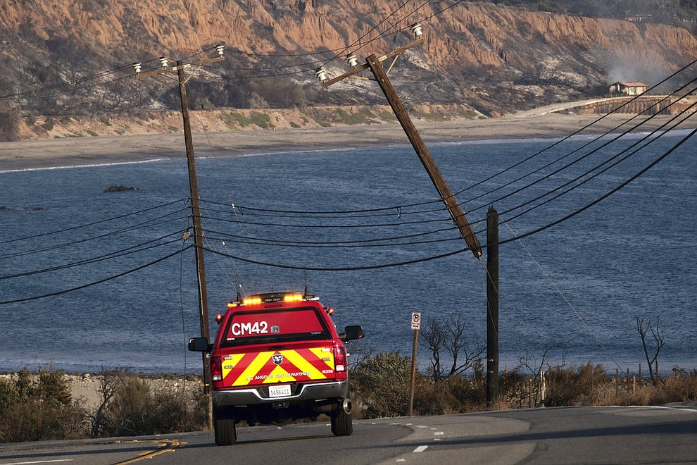 A Los Angeles Fire Department truck drives past burned and broken telephone poles along the coast down Pacific Coast Highway which remained closed in both directions outside of Malibu, Calif., on Saturday, Nov. 10, 2018. Firefighters have saved thousands of homes despite working in "extreme, tough fire conditions that they said they have never seen in their life," Los Angeles County Fire Chief Daryl Osby said. (AP Photo/Richard Vogel)