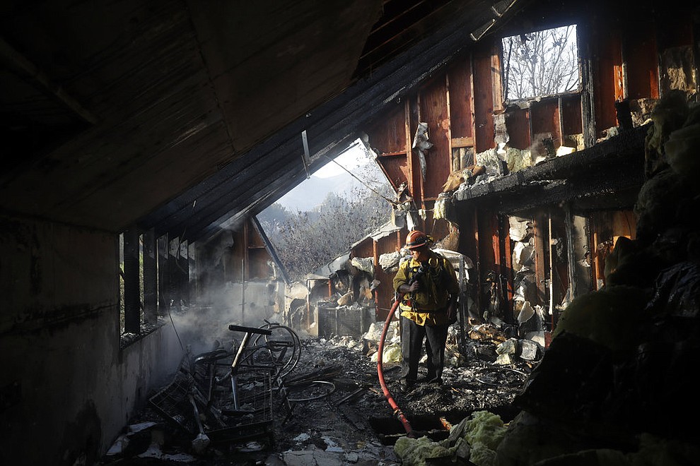 Capt. Adrian Murrieta with the Los Angeles County Fire Dept., looks for hot spots on a wildfire-ravaged home Saturday, Nov. 10, 2018, in Malibu, Calif. Scores of houses from ranch homes to celebrities' mansions burned in a pair of wildfires that stretched across more than 100 square miles of Southern California, authorities said Saturday. (AP Photo/Marcio Jose Sanchez)