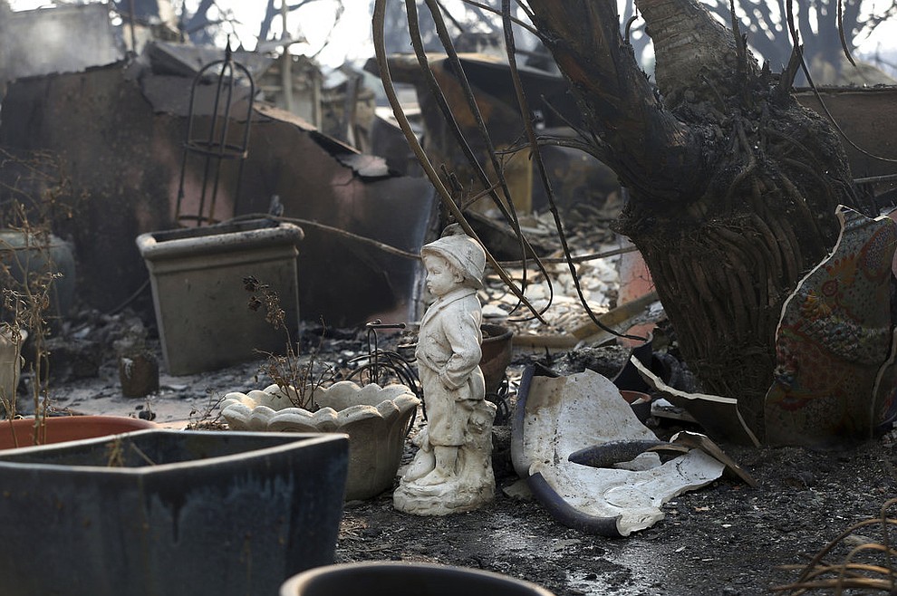 A statuary figure of a boy stands outside one of at least 20 homes destroyed just on Windermere Drive in the Point Dume area of Malibu, Calif., Saturday, Nov. 10, 2018. Known as the Woolsey Fire, it has consumed tens of thousands of acres and destroyed dozens of homes. (AP Photo/Reed Saxon)