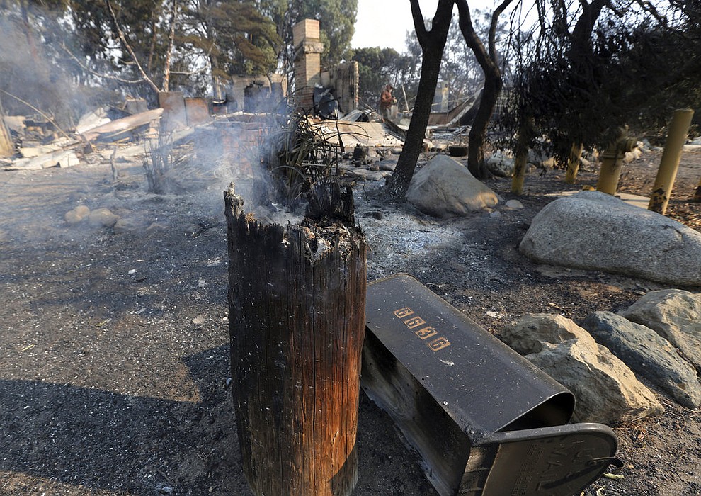 A man who gave his first name as John, background, looks over the ruins of his home, one of at least 20 homes destroyed just on Windermere Drive in the Point Dume area of Malibu, Calif., Saturday, Nov. 10, 2018. Known as the Woolsey Fire, it has consumed tens of thousands of acres and destroyed dozens of homes. (AP Photo/Reed Saxon)