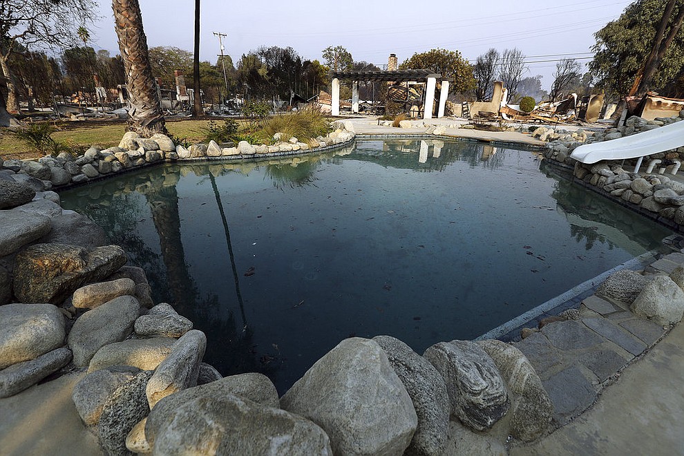 A swimming pool is behind one burned home, with others at left, some of at least 20 homes destroyed just on Windermere Drive in the Point Dume area of Malibu, Calif., Saturday, Nov. 10, 2018. Known as the Woolsey Fire, it has consumed tens of thousands of acres and destroyed dozens of homes. (AP Photo/Reed Saxon)