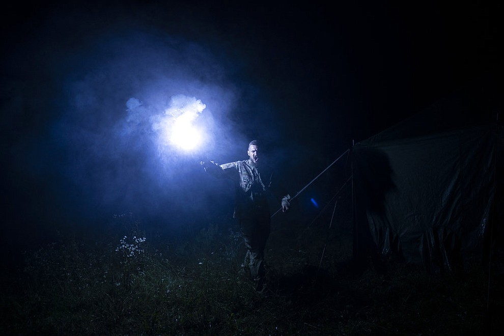 In this July 29, 2018 photo, instructor Georgiy Barylenko, holds a flare as he instructs young participants of the "Temper of will" summer camp, organized by the nationalist Svoboda party, during a night drill in a village near Ternopil, Ukraine. (AP Photo/Felipe Dana)