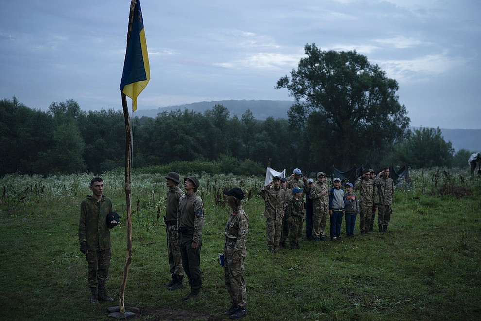 In this July 28, 2018 photo, young participants and instructors of the "Temper of will" summer camp, organized by the nationalist Svoboda party, stand in formation as they sing the national anthem in a village near Ternopil, Ukraine. Earlier this year, the Ministry of Youth and Sports earmarked 4 million hryvnias (about $150,000) to fund some of the youth camps among the dozens built by the nationalists. (AP Photo/Felipe Dana)